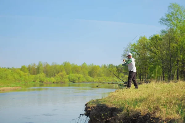 Pescador lanzando el cebo con una varilla giratoria. Actividad al aire libre. Foto con profundidad de campo poco profunda tomada en abertura abierta amplia . —  Fotos de Stock