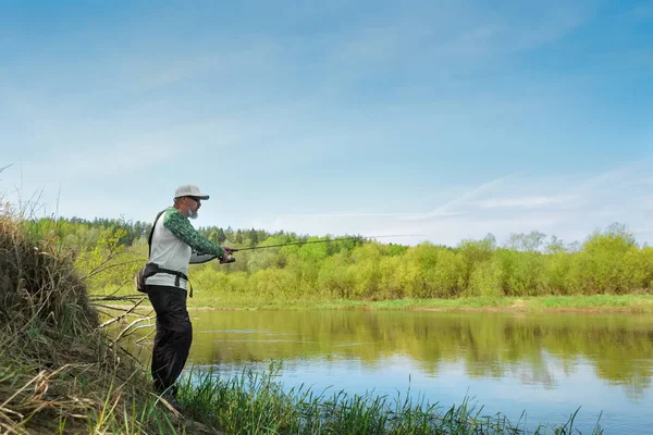 Pescador tentando fazer um elenco perfeito, jogando isca. Spining pesca, pesca, captura de peixe. Passatempo e férias. Foto com profundidade de campo rasa tirada em ampla abertura aberta . — Fotografia de Stock