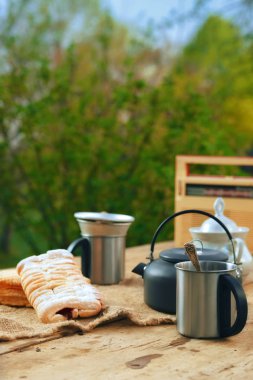 Açık havada masada bir kupa ve bisküvi ile kamp su ısıtıcısı . Yaz akşamı atıştırmalık.  
