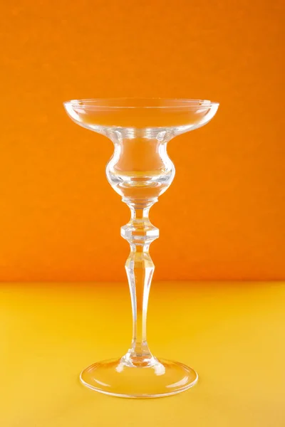 Empty glass for cocktail or dessert on orange background — Stock Photo, Image