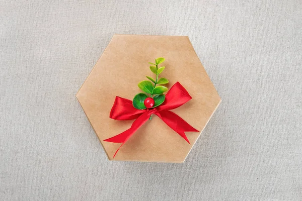 Caixa de presente de papelão artesanal hexagonal com nó de arco vermelho — Fotografia de Stock