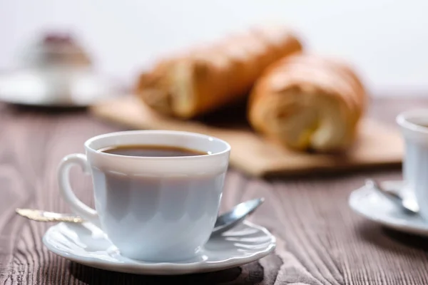 Bollos laminados y café sobre mesa de madera a la luz del sol de la mañana. Foto con poca profundidad de campo . —  Fotos de Stock