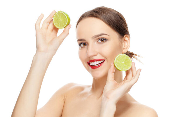 Lovely girl holding two halves of fresh lime in both hands, looking straight. Smiling model with healthy skin.