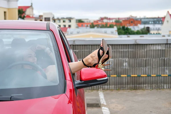 Chica sobresaliendo de sus piernas de la ventana del coche — Foto de Stock