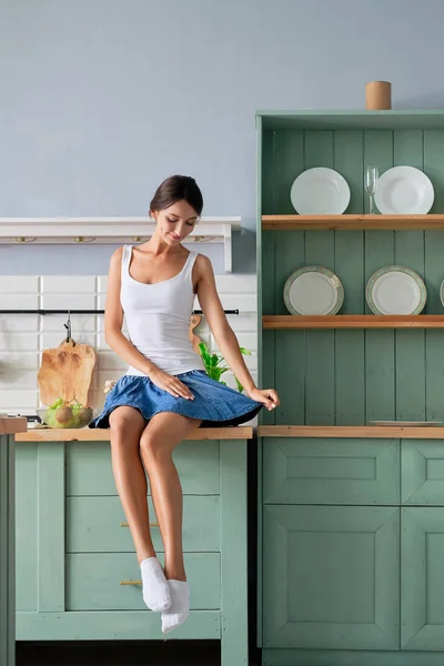 Menina bonita sentada na mesa em sua cozinha e esperando o café da manhã — Fotografia de Stock