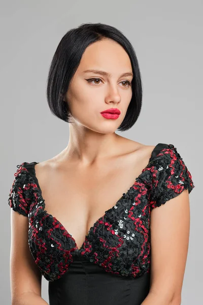 Serious lady with short dark hair and red lips posing in studio