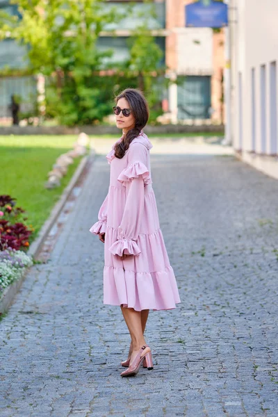 오버사이즈 핑크 드레스를 입은 젊고 세련된 소녀의 야외 도시 초상화 — 스톡 사진