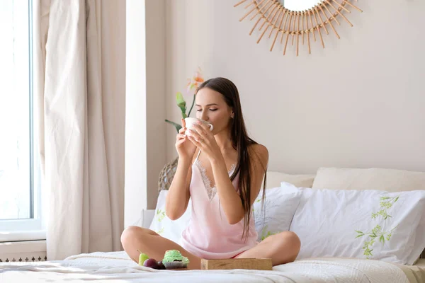 Niedliches Mädchen trinkt Tee im Bett in sonnigem Morgen — Stockfoto