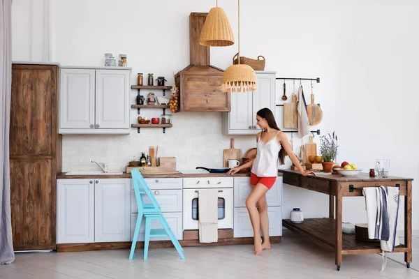 Estilo de vida foto de menina bonito em pé junto ao fogão na cozinha, cozinhar e cheirar aromas agradáveis de fritar comida — Fotografia de Stock
