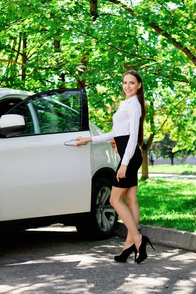 Hermosa chica abre la puerta de su coche y va a sentarse en el asiento del conductor — Foto de Stock