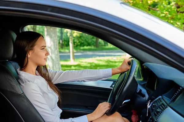 Linda menina morena sorridente ao volante de um carro — Fotografia de Stock