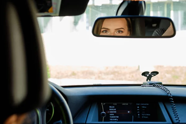 Reflexão de olhos femininos no espelho retrovisor de um carro — Fotografia de Stock
