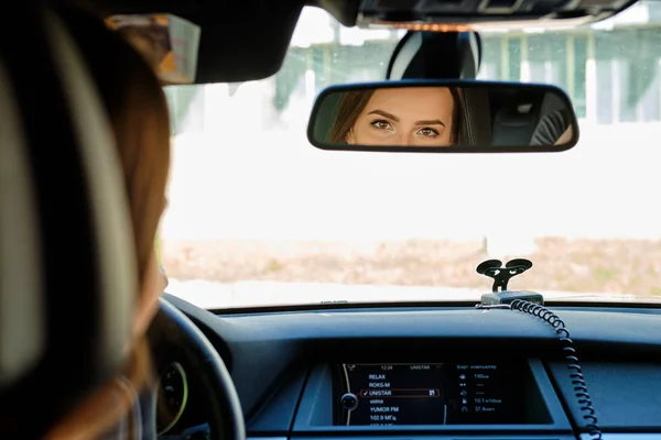 Reflejo de los ojos femeninos en el espejo retrovisor de un coche — Foto de Stock