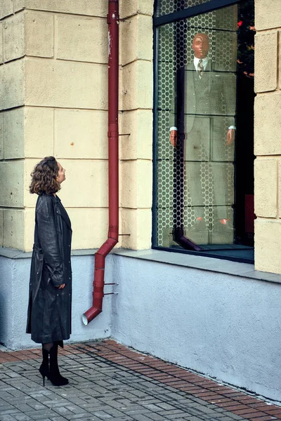 Señora mirando el escaparate en traje de hombre de pie en la calle — Foto de Stock