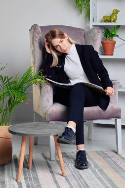 Dergi ile oturma odasında oturan kot pantolon ve ceket kız 