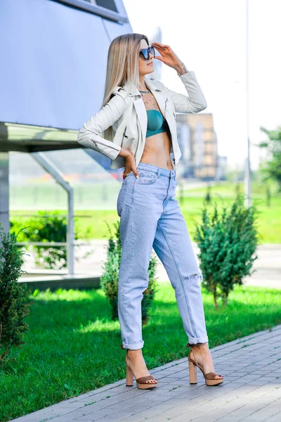 Jolie dame en jean bleu et veste en cuir blanc profitant du soleil — Photo