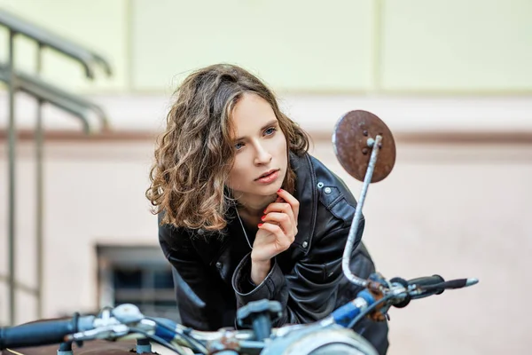 Senhora bonita em casaco de couro e cabelo encaracolado selvagem olhando para rer ver espelho de moto vintage velho — Fotografia de Stock