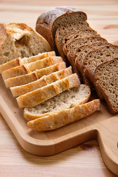 Pain blanc et brun sur planche à découper en bois — Photo