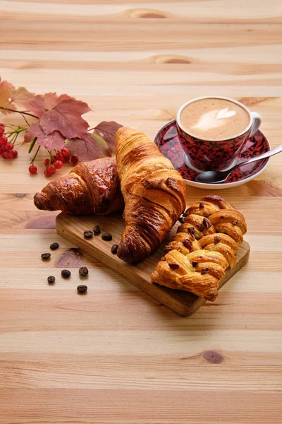 Bollo de pasas de hojaldre y croissant crujiente en mesa de madera con café —  Fotos de Stock