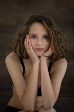 Güzel ve nazik bir kız. Elleri yüzüne yakın poz veriyor.