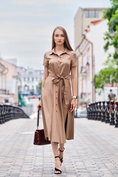 다우 거리를 걷고 있는 길고 아름다운 올리브 드레스를 입은 아름다운 모델 — 스톡 사진