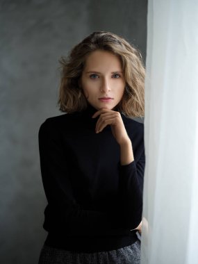 Pencerenin yanında siyah kazaklı dalgın kız.