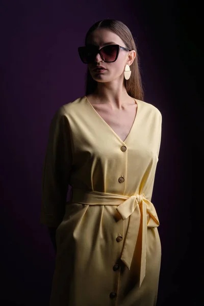 Modèle de mode en grandes lunettes de soleil portant une robe jaune avec des boutons — Photo