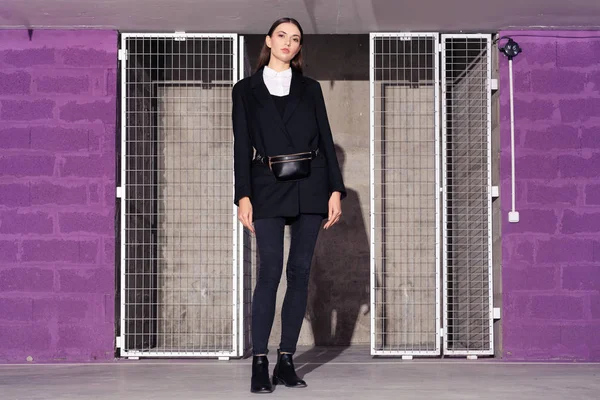 검은 자켓 과 청바지를 입은 소녀가 금속 격자 문을 들고 기술 실 근처에서 있습니다. — 스톡 사진