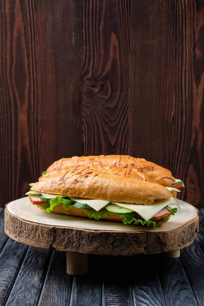 Сандвіч з шинкою, огірком, сиром чеддара на дерев'яній дошці. — стокове фото