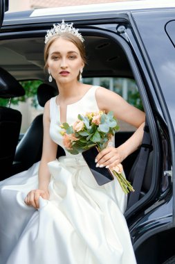 Güzel gelin arabanın arka koltuğunda oturur. 