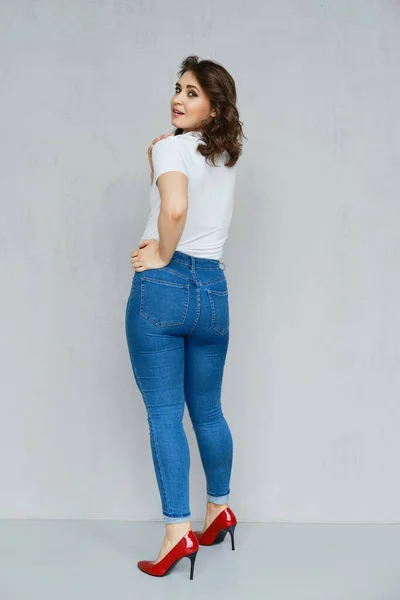 Chica Positiva Jeans Camiseta Blanca Tacones Rojos Posando Cerca Pared — Foto de Stock