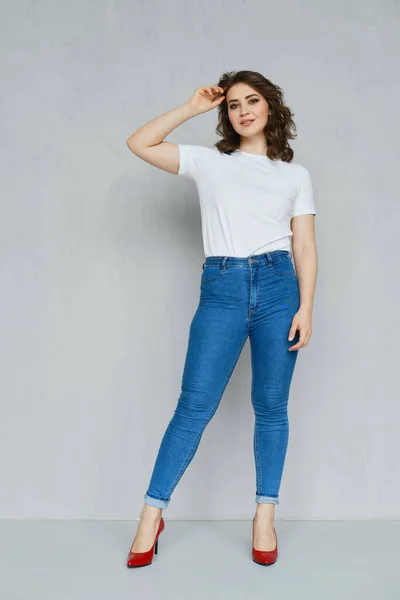 Positief Meisje Jeans Wit Shirt Rode Stiletto Poseren Bij Muur — Stockfoto