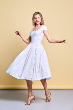 Stüdyoda beyaz elbiseler içinde dönen güzel, neşeli genç bir kadın.
