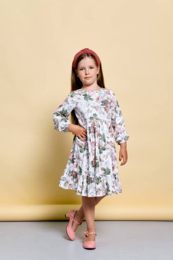 Stüdyoda soluk sarı arka planda poz veren güzel bir kız.