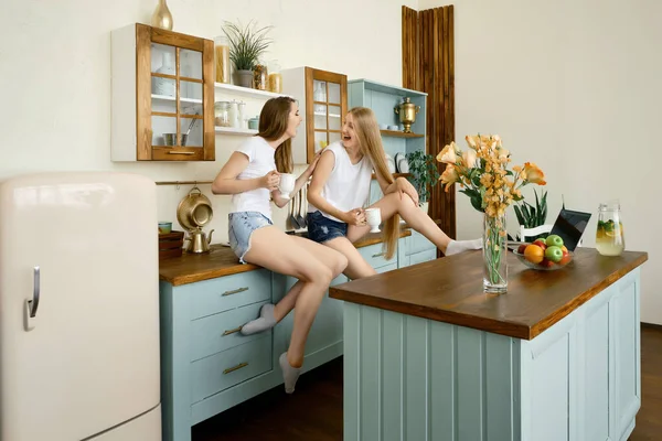 Δύο Νεαρές Αστείες Γυναίκες Λένε Ιστορίες Και Γελάνε Στην Κουζίνα — Φωτογραφία Αρχείου