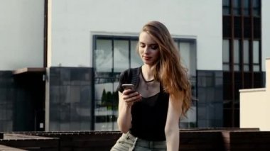 Neşeli genç bir kadın akıllı telefondan sosyal ağı kaydırıyor.