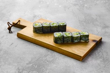 Tahtaya salatalık, avokado ve peynir konmuş küçük rulo.