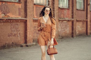 Kulaklıklı güzel bir kadın kaldırımda yürüyor.