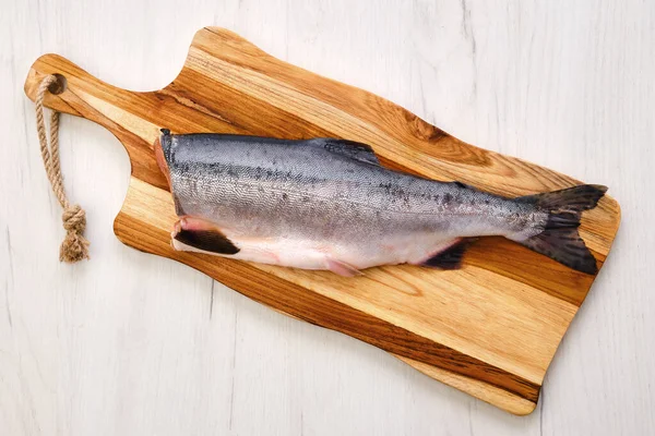 木制切菜板上新鲜无头粉红鲑鱼的俯视图 — 图库照片