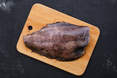 Ahşap kesme tahtasının üzerinde kafası olmayan taze halibut manzarası.