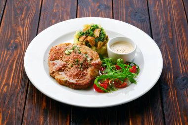 Kızarmış pirzola, patates püresi ve taze domates ve roka ile servis edilen edulis soslu domuz pirzolası.