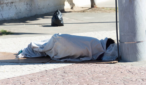 Salvador, Bahia, Brazil - July 20, 2025: View of a homeless man sleeping on the ground next to an electric pole in the city of Salvador, Bahia.