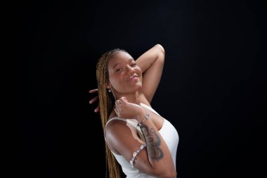 Salvador, Bahia, Brezilya - 30 Ağustos 2025: Siyah bir arkaplan karşısında örgülü saçlarıyla bir stüdyo fotoğrafı için poz veren genç bir kadın. Salvador, Brezilya.