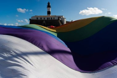 Salvador, Bahia, Brezilya - 14 Eylül 2025: İnsanlar ve büyük bir gökkuşağı bayrağı, Brezilya 'nın Salvador kentindeki Barra deniz feneri yakınlarındaki bir LGBT etkinliğinde protesto ederken görülüyor.
