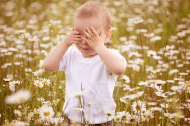portrait  baby toddler sitting in rural field with flowers and sneezing from seasonal pollen allergy clipart