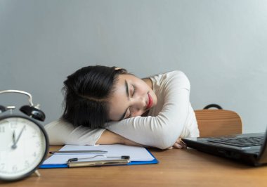 Virüs salgını sırasında evden çalışma. İş kadını geç saatlere kadar çalışıyor ve masadaki yorgunluk yüzünden uyuyor, iş konsepti.