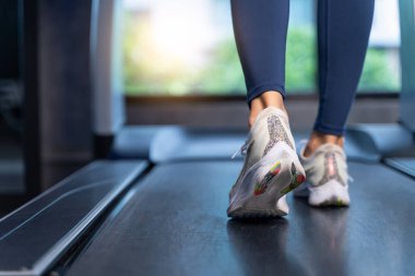 Spor salonundaki koşu bandında kadınların ayakları koşuyor. Kadınlar esniyor, spor ve sağlıklı kavramlar için kardiyodan önce ısınıyorlar.