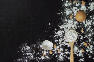 Ahşap kaşıkta un ve ahşap masada yumurta kabuğu pişirmek için.