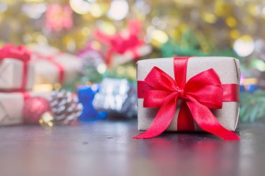 Noel için ahşap masada kırmızı kurdeleli el sanatları hediye kutusunu kapat ya da yeni yıl dekorasyonu arka planında