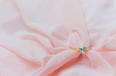 Sevgililer Günü ya da düğün arkaplanı için pembe kumaş üzerindeki elmas yüzüğü kapat